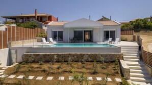 Une maison moderne dotée d’une piscine, d’un patio couvert et d’un mur de soutènement en pierre.