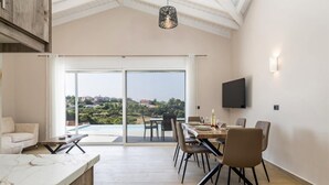 Un espace repas moderne avec une grande table, des chaises et un téléviseur fixé au mur.