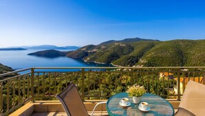 A balcony with a table and chairs overlooking a scenic view of a lake and hills. - Villa Inna With 3 Bedrooms and 4 Bathrooms (Lefkada)