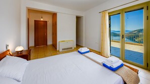 A hotel room with two beds, a heater, a window with a view of the sea, and a balcony. - Villa Inna With 3 Bedrooms and 4 Bathrooms (Lefkada)