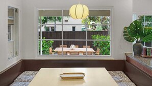 A room with a large window, a wooden table, and a bench. - The OB Hideaway, pool, hot tub (San Diego)