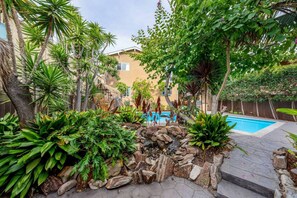 A pool surrounded by tropical plants and a stone wall.