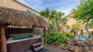 A hot tub with a thatched roof, surrounded by tropical plants and a stone pathway. - The OB Hideaway, pool, hot tub (San Diego)