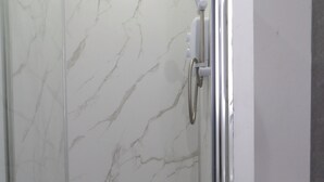 A glass-enclosed shower with a white marble wall and a toilet to the right. - 2bed Apt Sleeps 4-near Meadows Park, Parking, Wifi (Edinburgh)