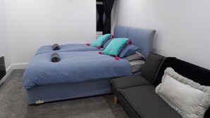 A bedroom with two beds, a sofa, and a window with curtains. - 2bed Apt Sleeps 4-near Meadows Park, Parking, Wifi (Edinburgh)