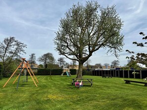 Relax in a serene outdoor space with a swing set, picnic table, and play structure for kids.