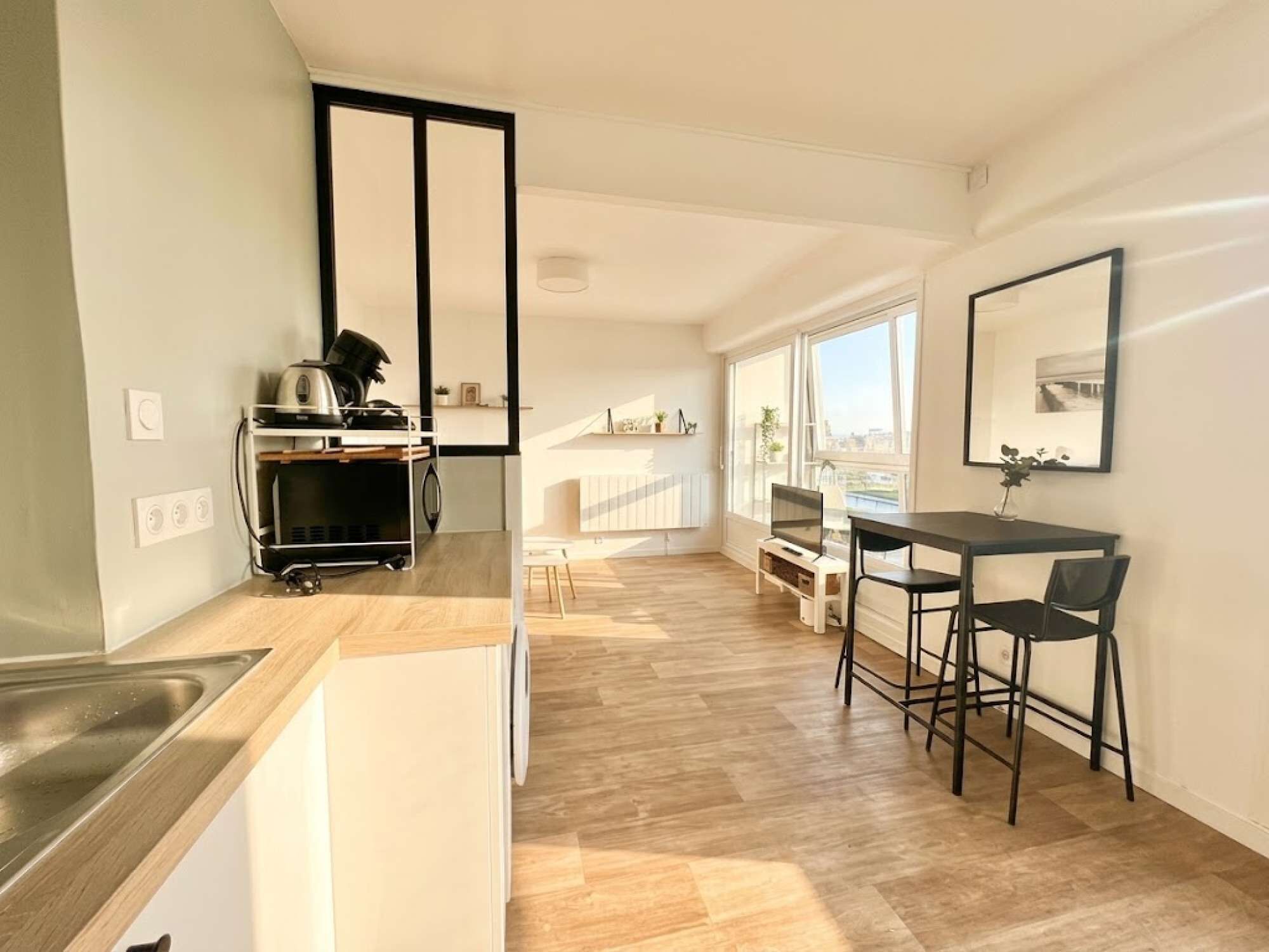 Una cocina moderna con encimera de madera, horno integrado y zona de comedor con mesa y sillas.