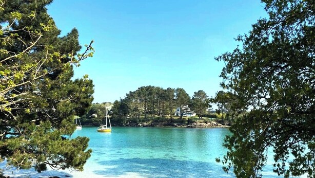 A tranquil lake with clear water, surrounded by trees and a small island. - -HANSEL- Belle Chaumière à Kerascöet (Névez)
