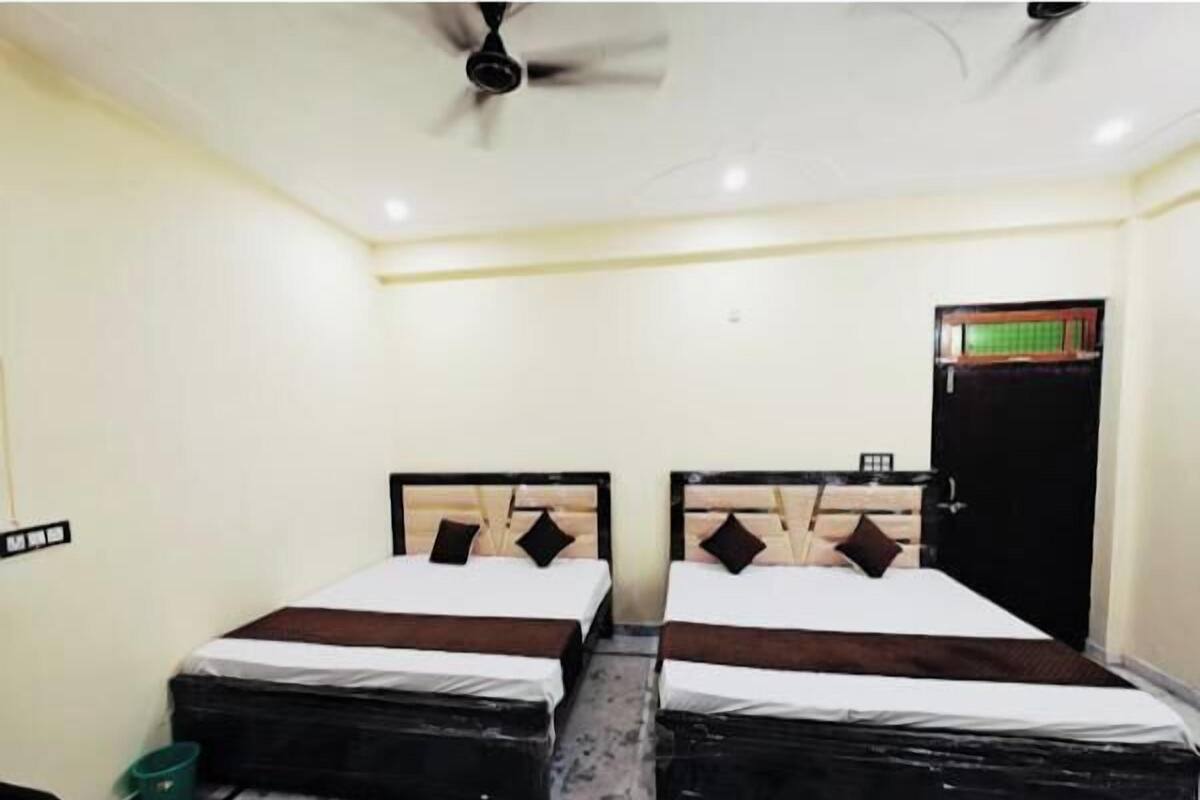 A room with two beds, a ceiling fan, and a door with a window.