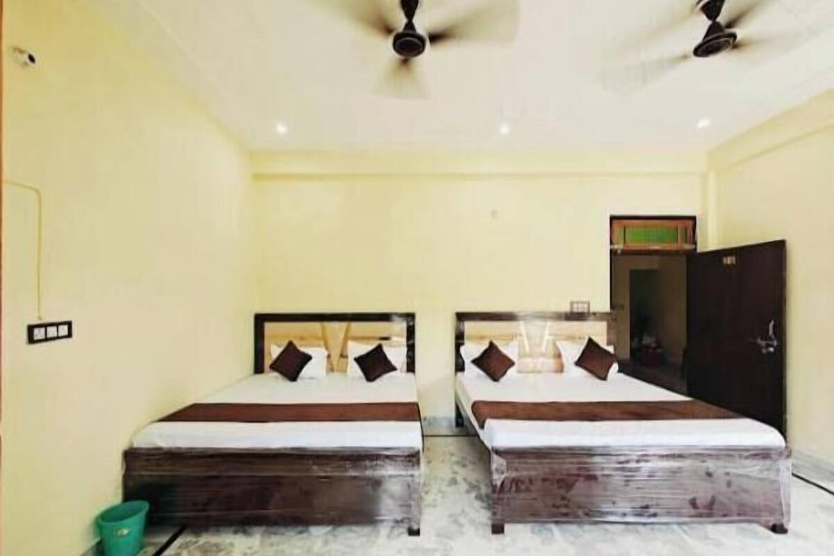 A room with two beds, a ceiling fan, a green bucket, and a door.