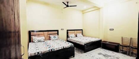 A bedroom with two beds, a ceiling fan, and a small desk.