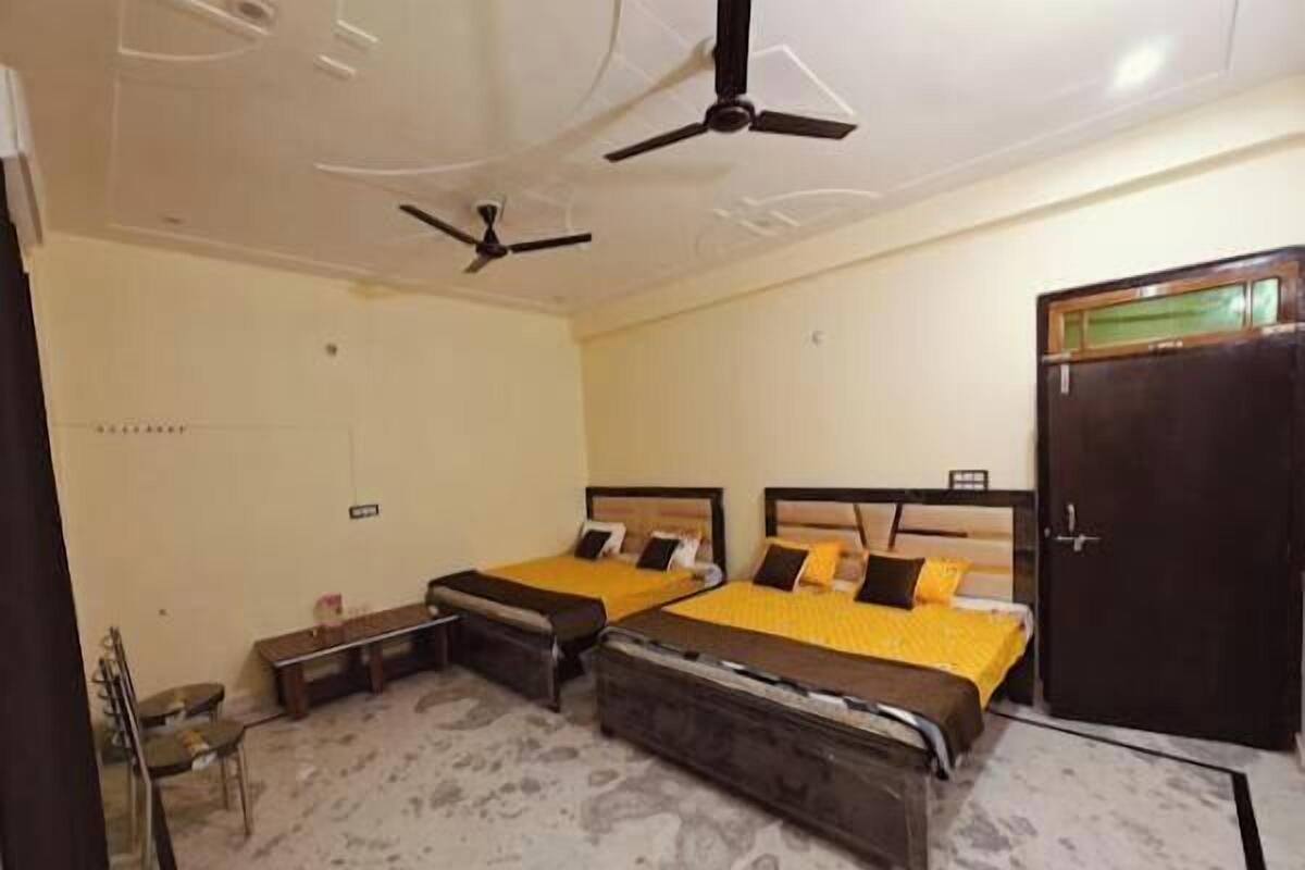 A bedroom with two beds, a ceiling fan, a wardrobe, and a small table.