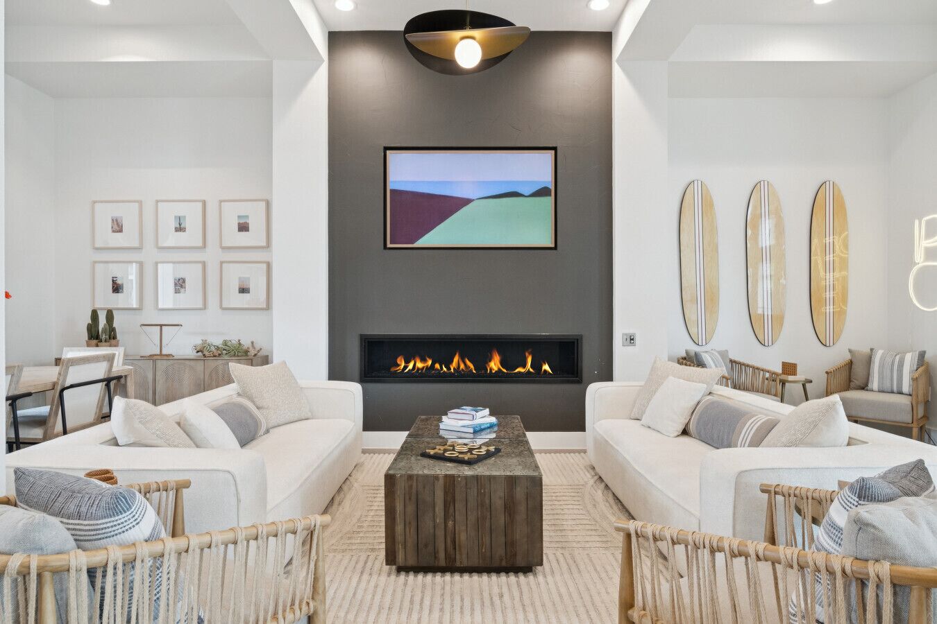 Un salon moderne avec une cheminée, deux canapés, une table basse et des tableaux encadrés accrochés au mur.