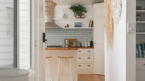 Una cocina moderna con armarios blancos, encimera de madera y dos taburetes de bar.