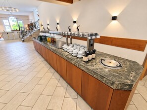 A buffet setup with a marble countertop, wooden cabinets, and wall-mounted light fixtures.