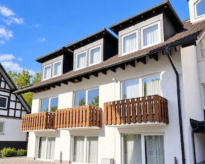 A two-story building with a balcony, large windows, and a tiled roof.