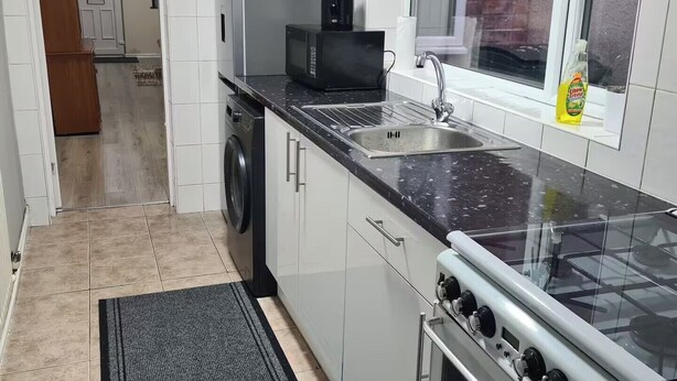 Une cuisine équipée d’un lave-linge, d’un four à micro-ondes, d’un évier et d’une cuisinière.