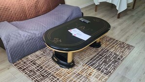 Une pièce comprenant un canapé, une petite table ronde recouverte d’une nappe blanche et une table basse sur laquelle se trouve une télécommande.