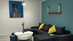 Una sala moderna con un sofá seccional, una mesa de centro redonda y un cuadro en la pared.
