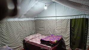 Ein Zelt mit Bett, einer Hängelampe und einer Wand mit Muster.