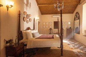 Un dormitorio tradicional con cama con dosel, suelo de madera y decoración en la pared.