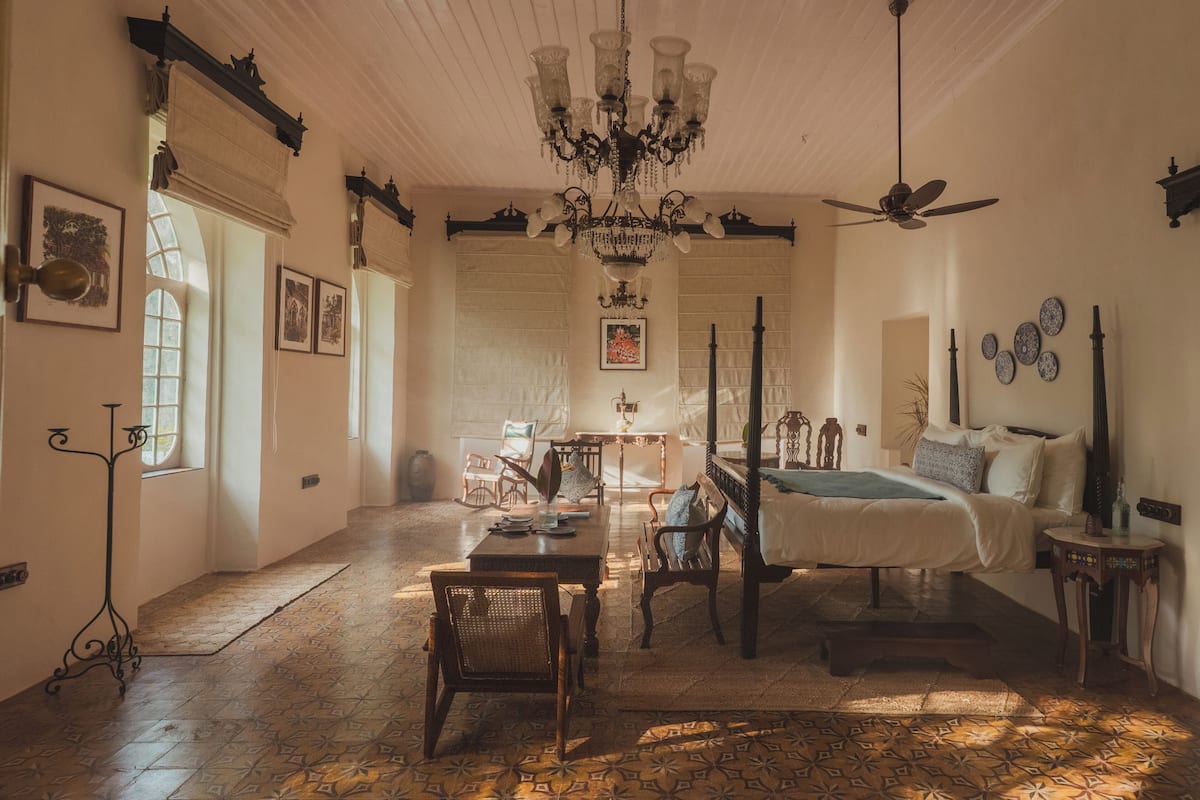 Een kamer met een bed, een kroonluchter, een eettafel en een stoel.