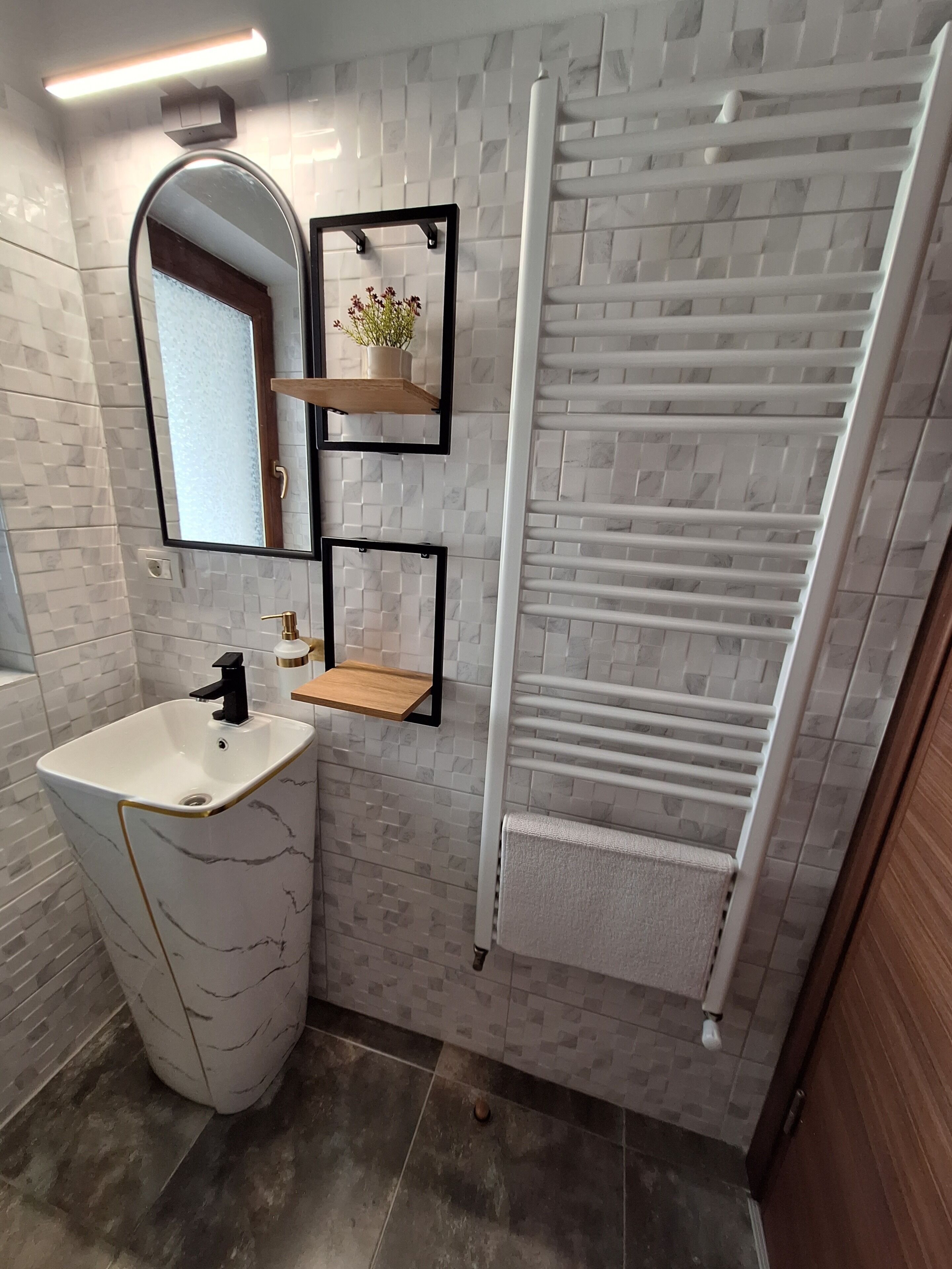 A bathroom with a white marble sink, a mirror, a towel rack, and a white towel hanging on it.