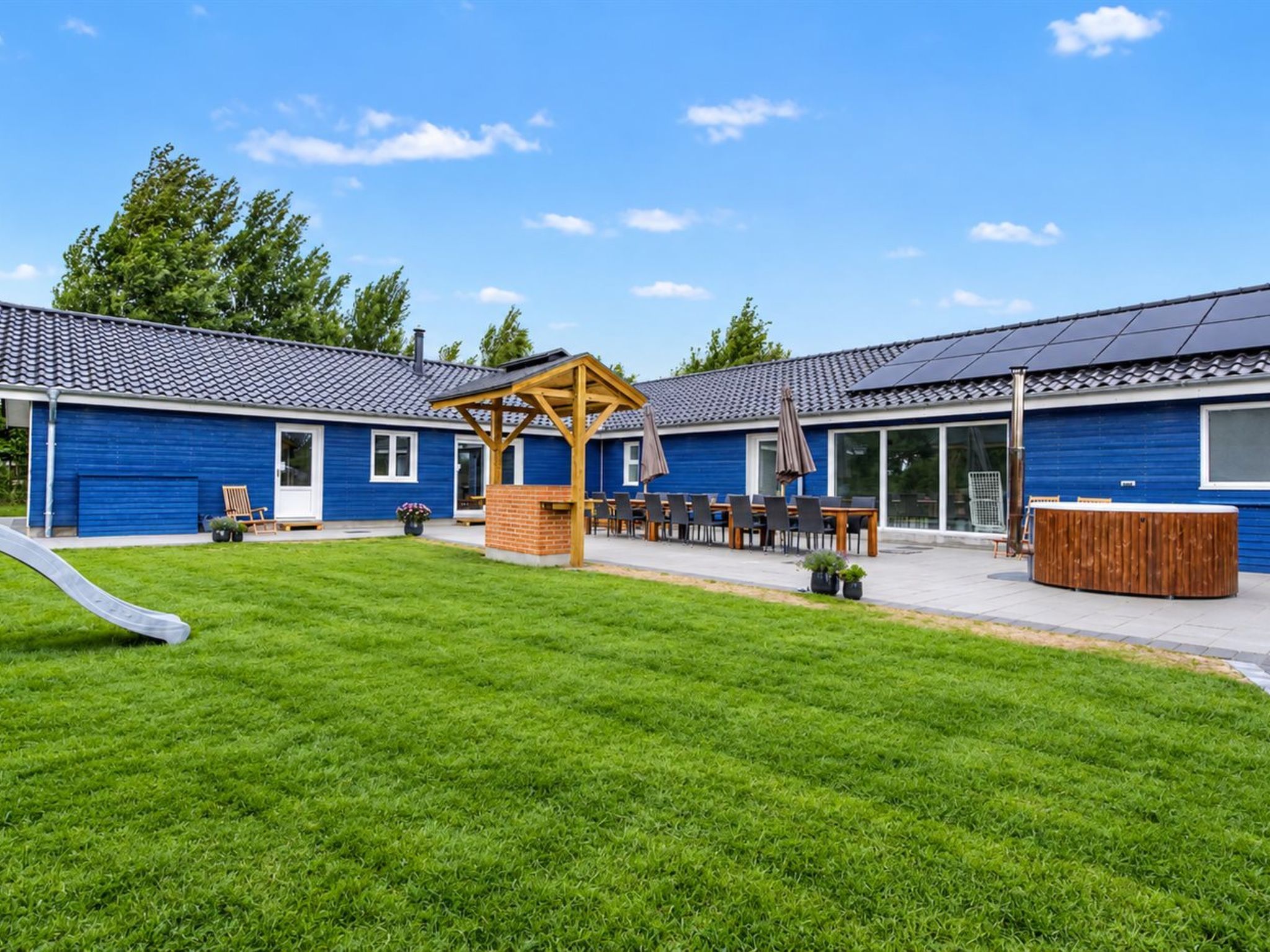 A blue building with a covered patio area, outdoor seating, and a slide.