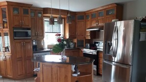 Une cuisine dotée de meubles en bois, d’appareils électroménagers en acier inoxydable et d’un îlot central.