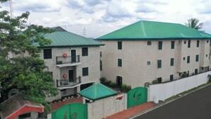 A two-story building with a green roof and a sign indicating it is a hotel. - Genesis Place  (Port Harcourt)