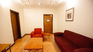 A room with a wooden table, two orange chairs, a red sofa, and a door with a sign. - Genesis Place  (Port Harcourt)