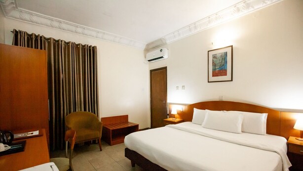 A hotel room with a large bed, a chair, a desk, and a wardrobe. - Genesis Place  (Port Harcourt)