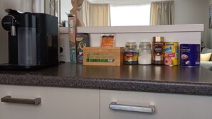 A kitchen with a coffee maker, tea kettle, and various food items on the counter. - Comfy & Sunny home in Wellington (Wellington)