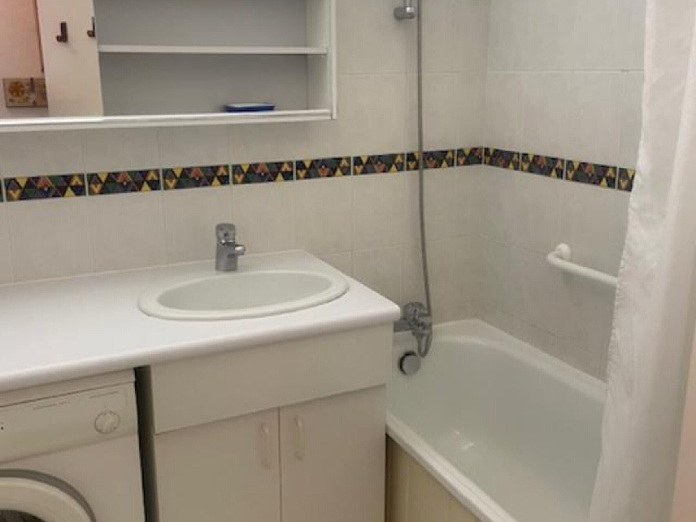 A bathroom with a white sink, a toilet, a washing machine, and a bathtub.