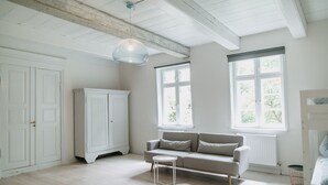 Ein Zimmer mit einem weißen Wandschrank, einem grauen Sofa, einem kleinen Tisch und einem Etagenbett.