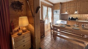 Un interior de madera con una mesa de comedor dispuesta para dos personas, una lámpara y un armario de madera.