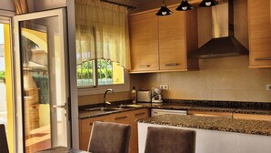 Una cocina moderna con armarios de madera, encimera de granito, lavavajillas integrado y un comedor con mesa y sillas.