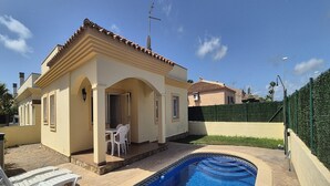 A small house with a swimming pool, a patio with chairs, and a green hedge. - House in Riumar: Family Charm with Private Pool (Deltebre)