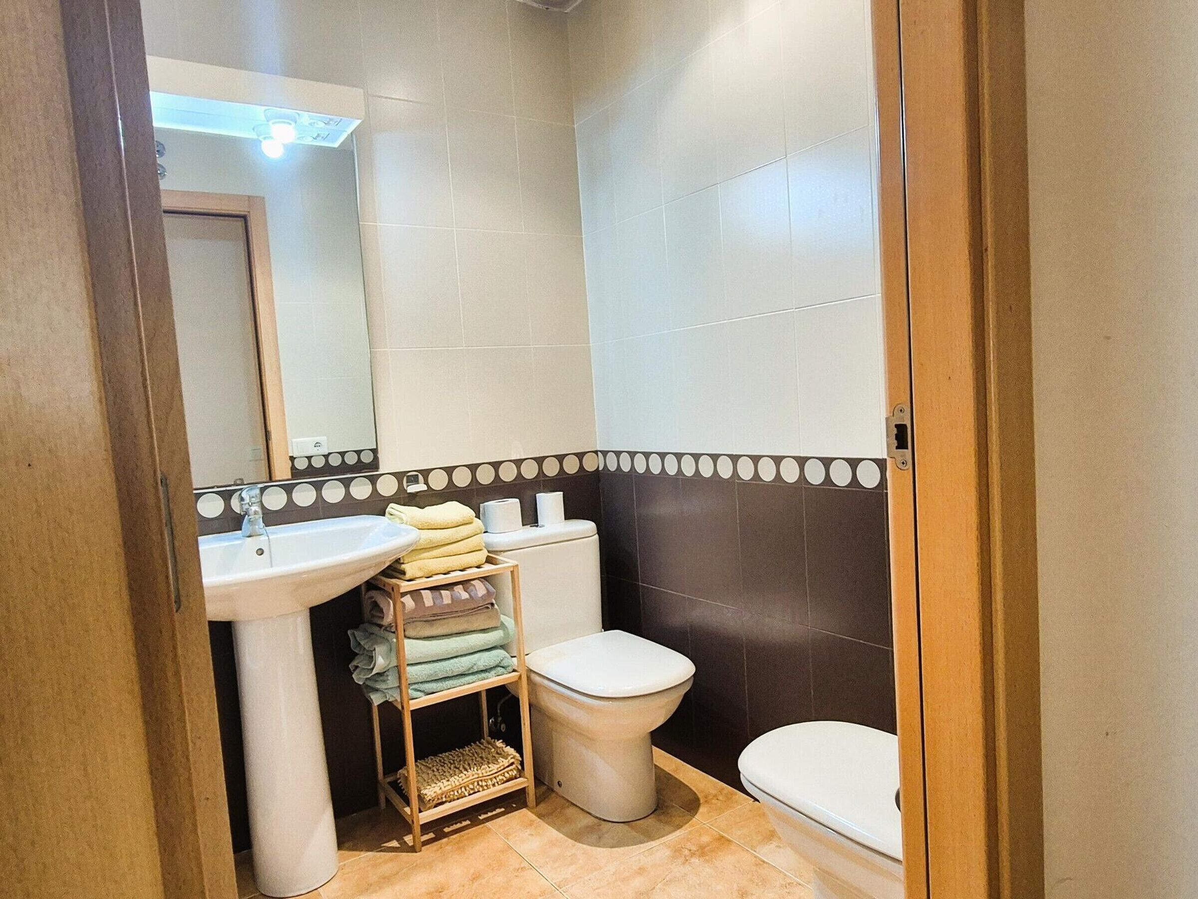 A small bathroom with a sink, toilet, and a mirror.