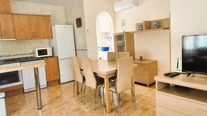 A compact kitchen with a microwave, refrigerator, and dining area with chairs and a table. - House in Riumar: Family Charm with Private Pool (Deltebre)