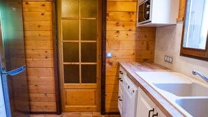A kitchen with wooden walls, a door with glass panels, a refrigerator, a dishwasher, and a sink. - Chalet for 8 near slopes in Grand-Bornand (Le Grand-Bornand)
