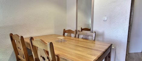 Una mesa de madera para comer con cuatro sillas, un espejo en la pared y un enchufe en la pared.
