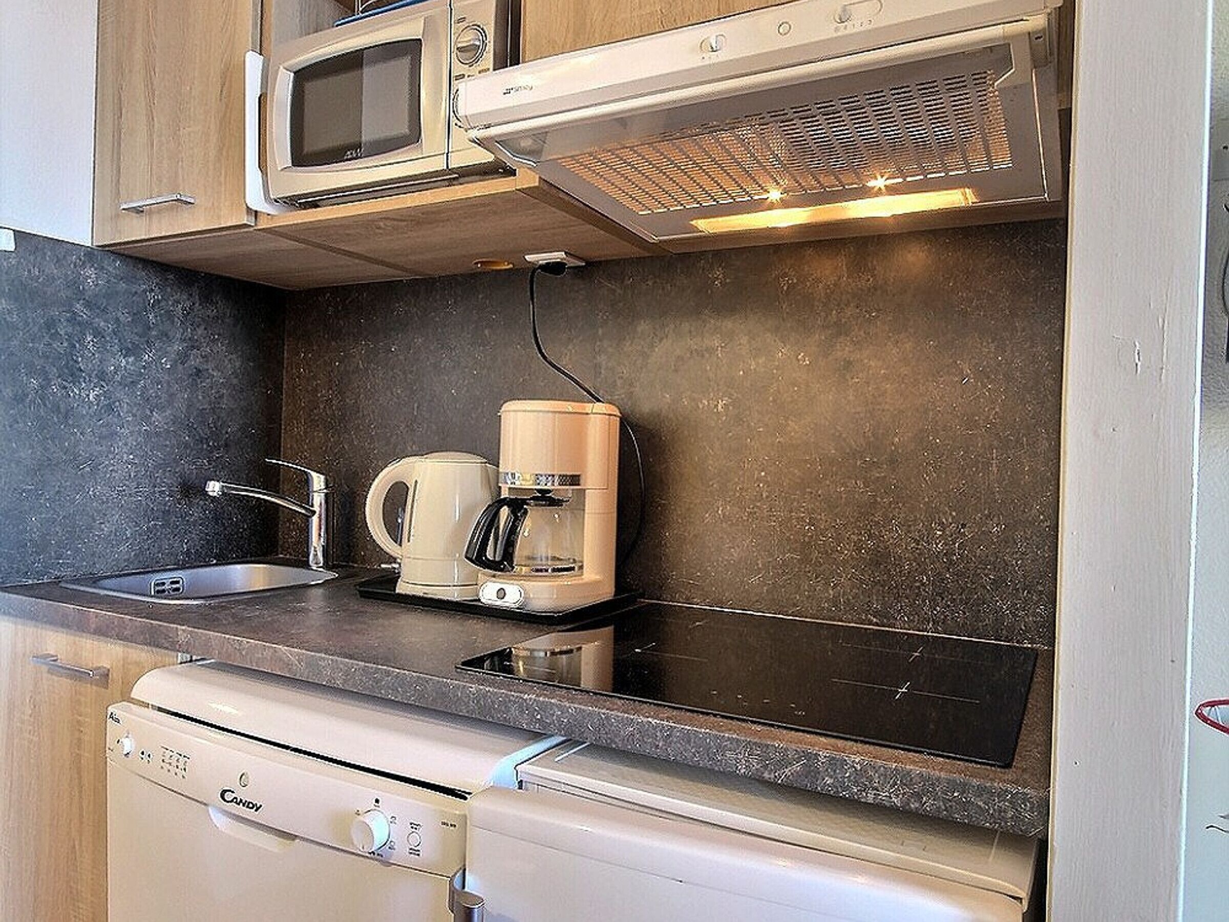 Una kitchenette compacta equipada con microondas, tostadora, cafetera y lavavajillas.