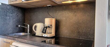 Una kitchenette compacta equipada con microondas, tostadora, cafetera y lavavajillas.
