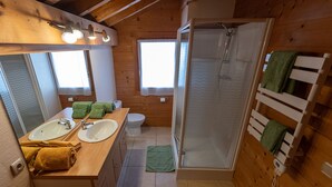 A compact wooden cabin bathroom with a shower, two sinks, and a mirror. - Spacious chalet for 10 near slopes with private parking (Le Grand-Bornand)