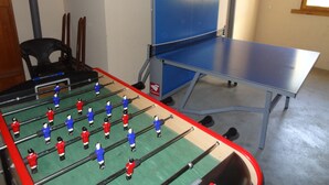 A foosball table with a blue table and red and white players, a black chair, and a blue cabinet. - Spacious chalet for 10 near slopes with private parking (Le Grand-Bornand)