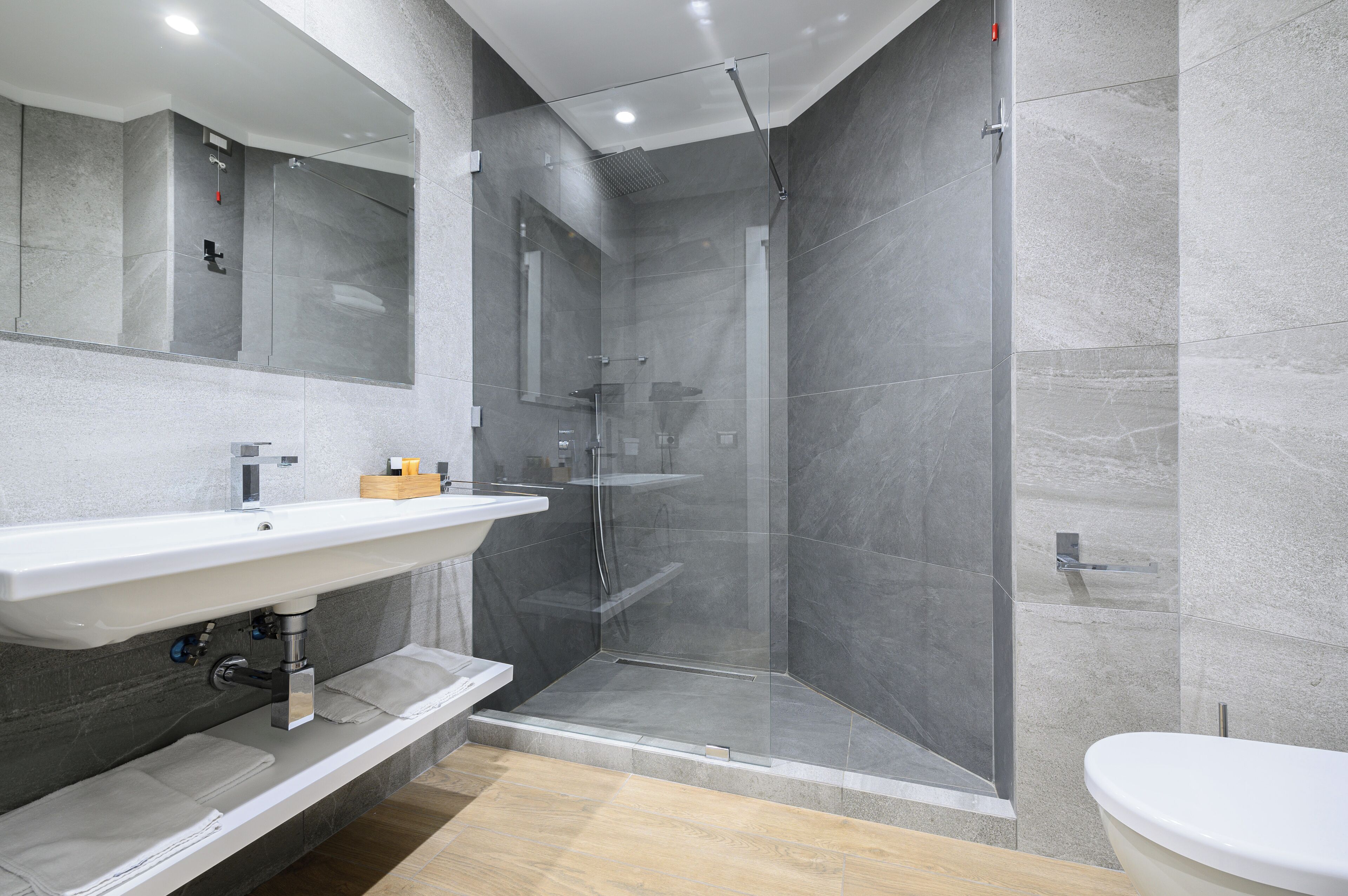 A modern bathroom with a glass-enclosed shower, a white sink, and a toilet.