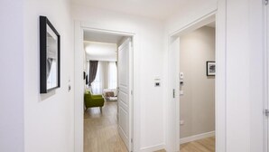 Un pasillo con una silla verde, una puerta blanca y un cuadro en la pared.