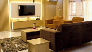 Una sala de estar moderna con un televisor de pantalla plana, asientos cómodos, una mesa de centro y una ampolla decorativa.