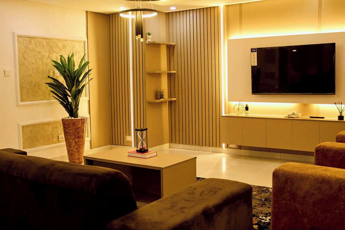 A modern living room with a sofa, coffee table, and a TV mounted on the wall.